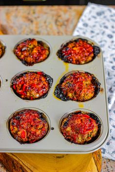 a muffin tin filled with lots of food on top of a wooden table