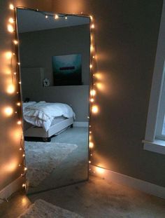 a bedroom with lights on the wall and a large mirror in front of it that is lit up