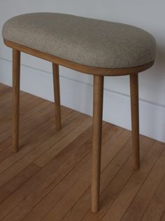 a close up of a wooden bench on a hard wood floor with a white wall in the background