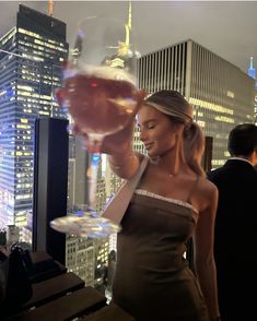 a woman holding a wine glass in front of a cityscape with skyscrapers