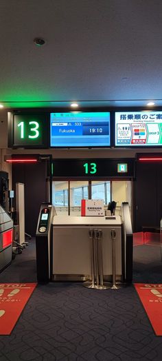 an airport check - in counter with electronic signs above it and red carpet on the floor