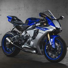 a blue and silver yamaha motorcycle parked in a garage with concrete walls behind it,