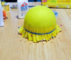 a yellow hat sitting on top of a wooden table next to other crafting supplies