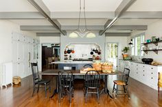 an open kitchen and dining room with hardwood floors, white walls, and ceiling beams