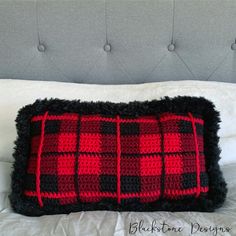 a red and black pillow on top of a bed