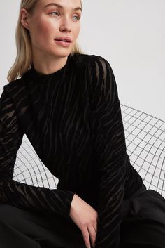 This top is mesh, elasticized and made of velvet and features a high neck. It has long sleeves. Black High Neck Top With Mesh Sleeves, Black Turtleneck Mesh Top With Sheer Sleeves, Black Turtleneck Mesh Top For Party, Black Turtleneck Top With Sheer Sleeves, Black Turtleneck Mesh Top For Night Out, Black High Neck Top With Sheer Sleeves, Black High Neck Mesh Top For Night Out, Black High Neck Mesh Top For Layering, Black Velvet Tops For Party