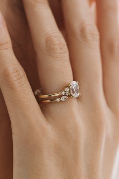 a woman's hand wearing a gold ring with an oval shaped diamond on it