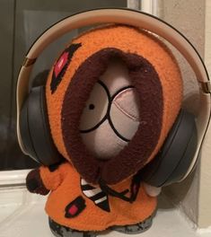 a stuffed animal wearing headphones on top of a window sill in front of a door