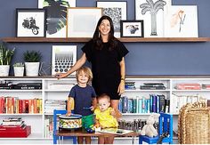 a woman standing next to two children in front of a book shelf filled with books