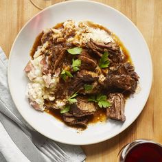 a white plate topped with meat, mashed potatoes and garnished parsley