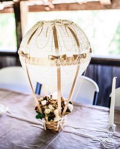 a table topped with a basket filled with flowers next to a light fixture on top of a wooden table