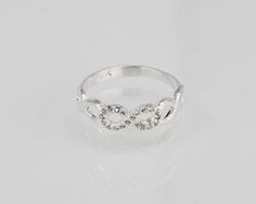 a white gold ring with three diamonds in the shape of two interlocked hearts