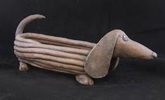 a wooden sculpture of a dachshund dog with long, curled legs on black background