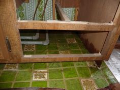 the inside of a kitchen cabinet with green tile on the floor and in between it is a sink