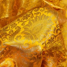 an orange and gold brocaded fabric with large, intricate designs on the side