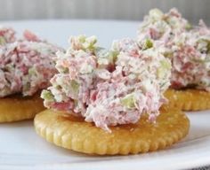 three crackers topped with crab salad on top of a white plate