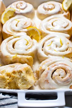 a pan filled with lemon rolls covered in icing and topped with sliced lemons