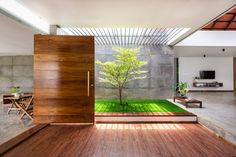 an open door leading to a living room with a tree in the center and green grass on the floor