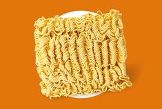 a plate of noodles on an orange background