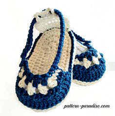 two crocheted baby shoes sitting on top of a white table next to each other