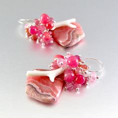 I love these focals! They are Argentine rhodochrosite gems and measure 22x20mm. They have been wrapped in sterling silver wire and dangle below a gorgeous combination of smooth ruby briolettes, pink moonstone, pink sapphire, white branch coral. Each bead is meticulously wrapped onto it's own head pin. The entire cluster is topped. I have used simple sterling ear wires. The earrings measure 1 3/4 (44mm.) from the top of the ear wires. Sterling Silver Pink Wire Wrapped Earrings, Pink Sterling Silver Wire Wrapped Earrings, Unique Pink Gemstone Earrings, Unique Pink Sterling Silver Earrings, White Branches, Black Freshwater Pearls, Pink Moonstone, Peacock Pearl, Handmade Lampwork Bead