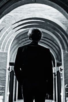 a man in a suit is walking through an archway with his back to the camera