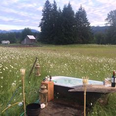 a bathtub sitting in the middle of a field with flowers and candles on it