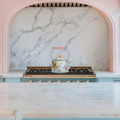 a tea pot sitting on top of a stove in front of a white marble wall