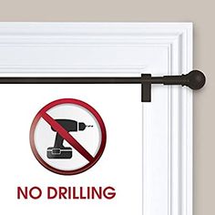 a no drilling sign hanging on the side of a white door with a black handle