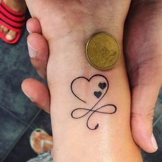 a couple holding hands with a small tattoo on the wrist that has hearts in it