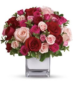 a bouquet of red, pink and white roses in a square vase