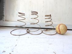 a baseball sitting on top of a white floor next to a metal wire christmas tree