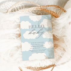 a hello baby book laying on top of a fluffy white blanket next to a wicker basket