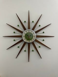 a clock on the wall with green balls in it's center and two hands