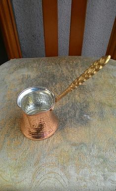 a metal cup sitting on top of a wooden chair