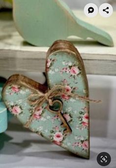 a heart shaped box sitting on top of a table next to a green bird figurine