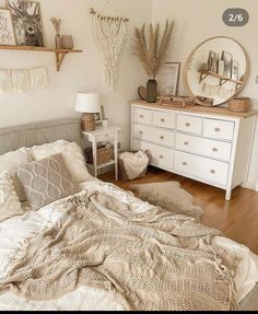 a white bed sitting in a bedroom next to a dresser and mirror on top of a wooden floor