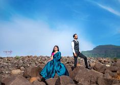 a man and woman are standing on rocks