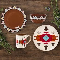 a wooden table topped with plates and cups filled with chocolate saucer next to evergreen branches