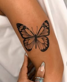 a woman's arm with a butterfly tattoo on the left side of her arm