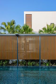 an outdoor swimming pool next to a tall white building with wooden slats on the side