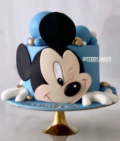 a mickey mouse cake on a blue plate with gold trimmings and black ears