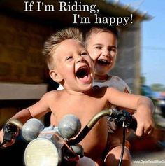 two young boys riding on the back of a motorcycle with their mouths open and laughing