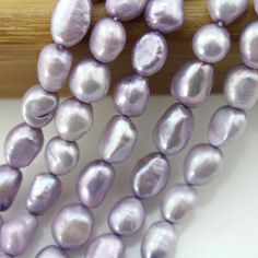 a bunch of purple pearls sitting on top of a wooden table next to a piece of wood