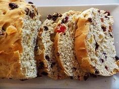 a loaf of bread with raisins and cranberries on it sitting on a white plate