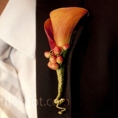 the man is wearing a boutonniere with an orange flower attached to it