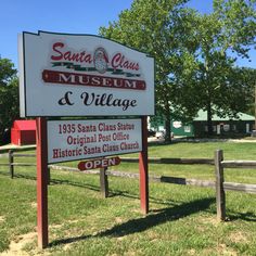 a sign for santa claus museum and village in front of a fenced in area