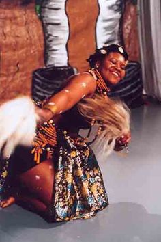 a woman is dancing on the floor with her hair blowing in the wind and wearing an elaborate dress