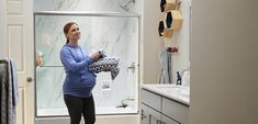 a woman standing in a bathroom holding a towel