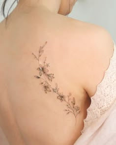 the back of a woman's shoulder with small flowers on her left side,